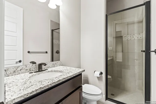 a bathroom with a granite countertop sink toilet and shower