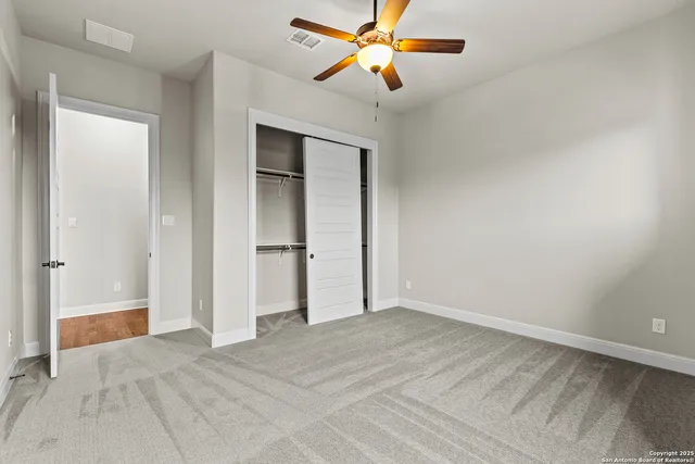 an empty room with closet and a ceiling fan