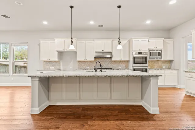 a large kitchen with kitchen island granite countertop a large window a sink and stainless steel appliances