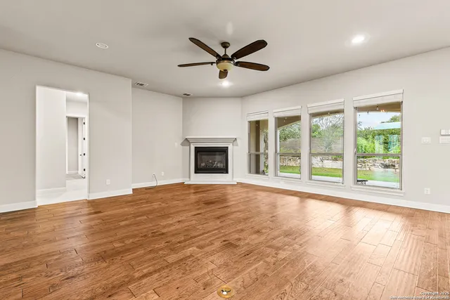 a view of an empty room with a window and a ceiling fan