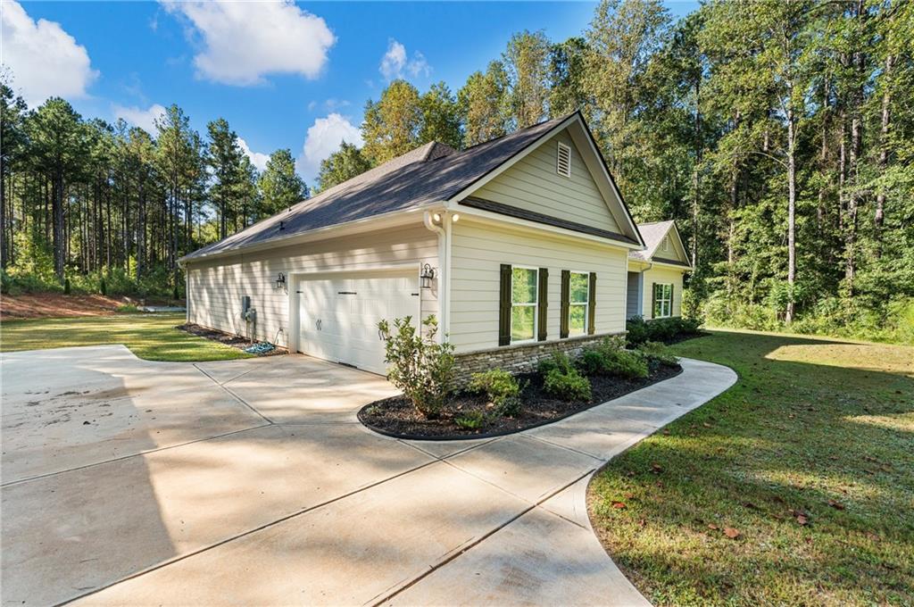 3696 Lee Road Salem, AL 36874 - Photo 2 of 36 Concrete driveway and walkway, two-car garage, stone accent siding, shuttered windows, and mature trees
