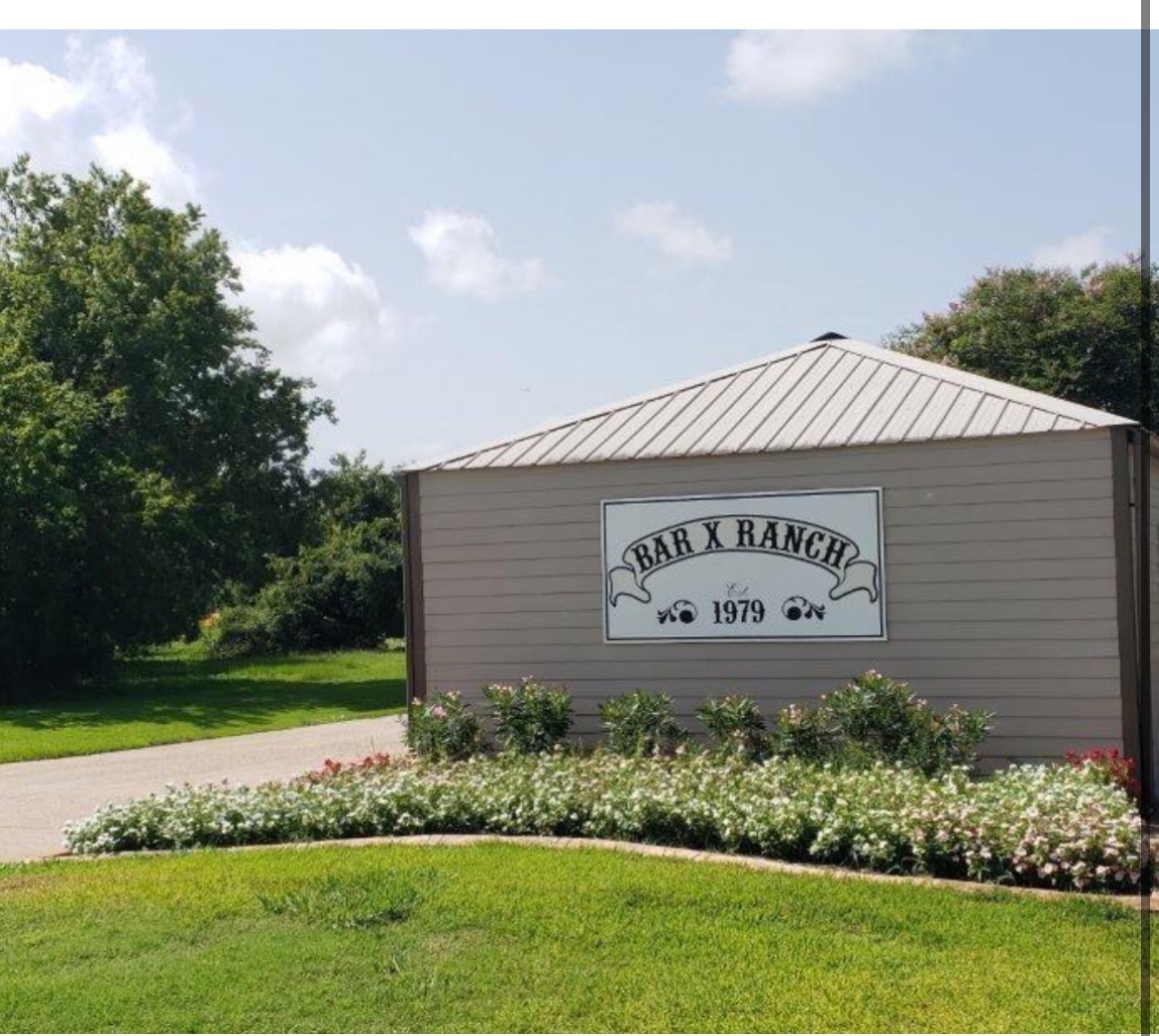 a sign of golf club on a wall under a tree