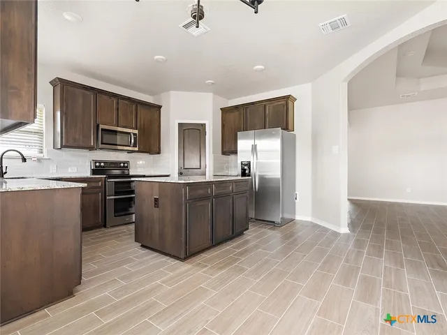 a kitchen with stainless steel appliances a stove a sink a microwave a refrigerator a counter top space and cabinets