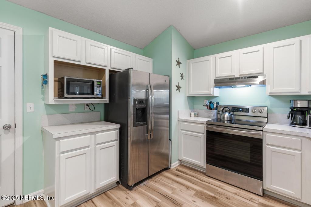 83096 St Mark Drive Yulee, FL 32097 - Photo 14 of 35 a kitchen with white cabinets and stainless steel appliances