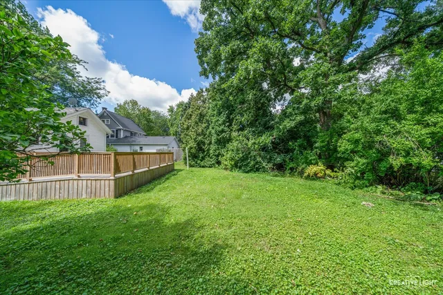 a view of a house with a big yard and large tree