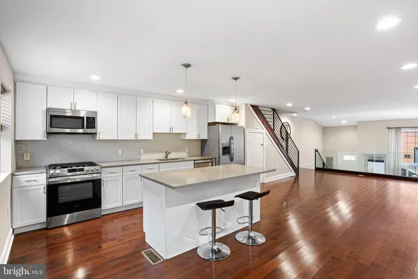 a kitchen with stainless steel appliances granite countertop a stove a refrigerator and a stove top oven with wooden floor