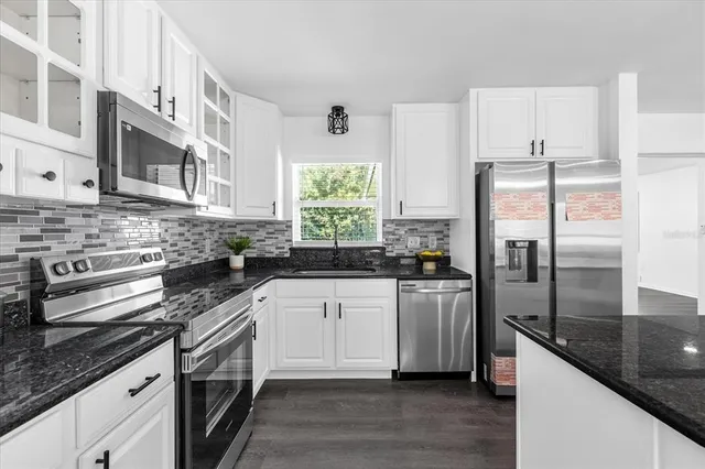a kitchen with stainless steel appliances granite countertop a refrigerator a stove and a sink