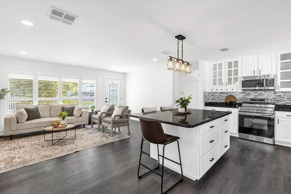 a kitchen with granite countertop a stove and white cabinets