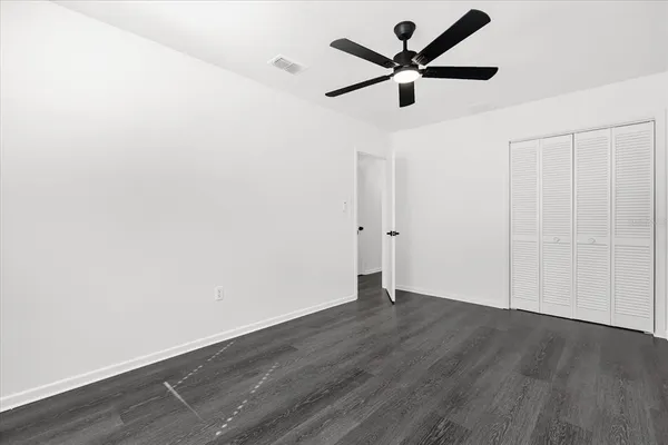 an empty room with wooden floor and ceiling fan