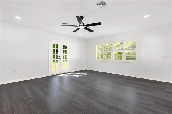 an empty room with wooden floor ceiling fan and windows