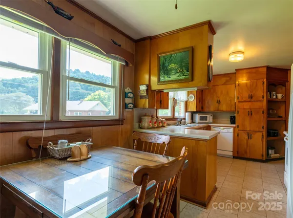 a kitchen with a refrigerator a stove top oven a sink dishwasher and dining table with wooden floor