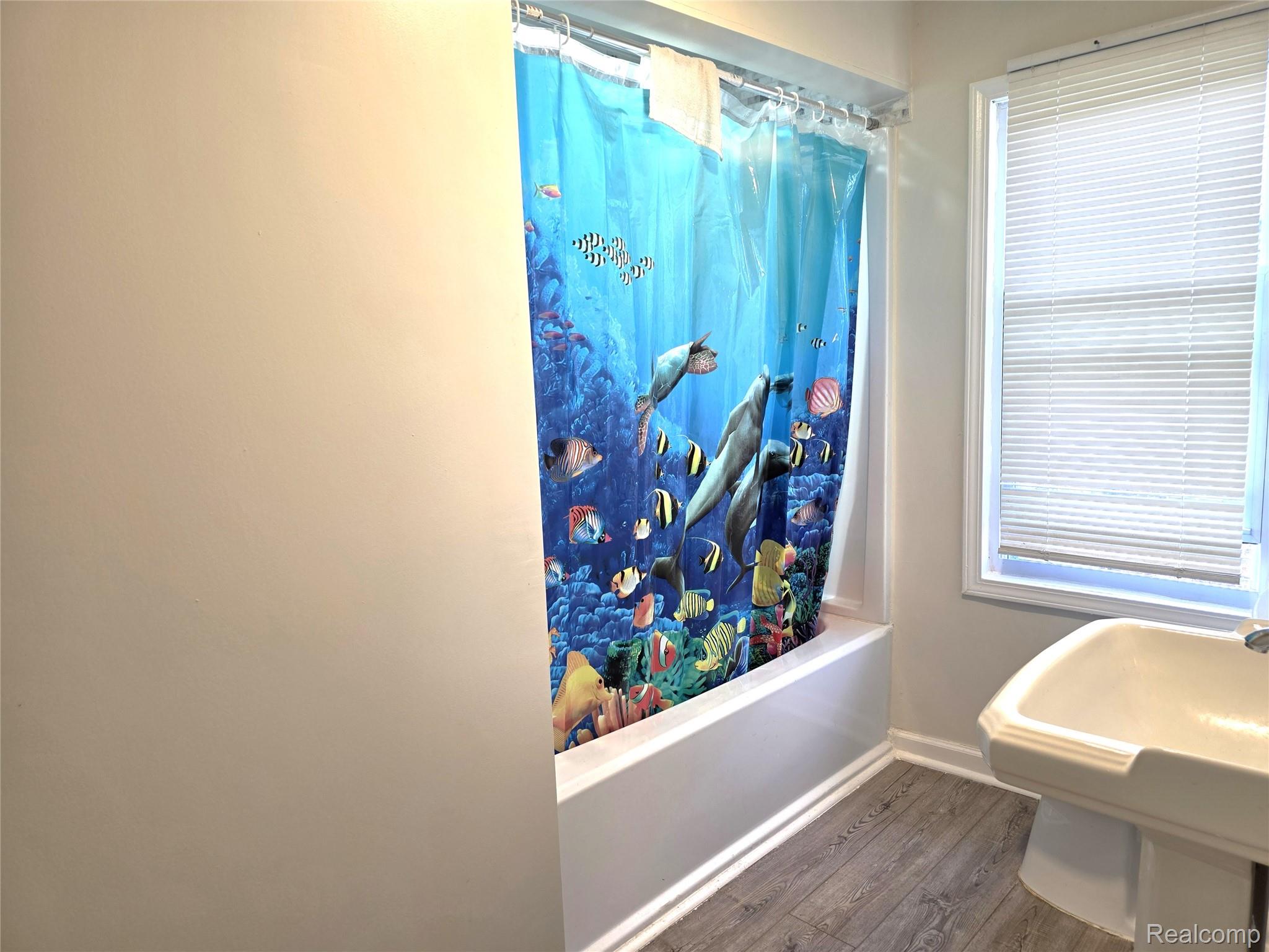 16814 Strathmoor Street Detroit, MI 48235 - Photo 15 of 31 Tub/shower combination, window with privacy blinds, pedestal sink, wood-finish flooring, and light-toned walls