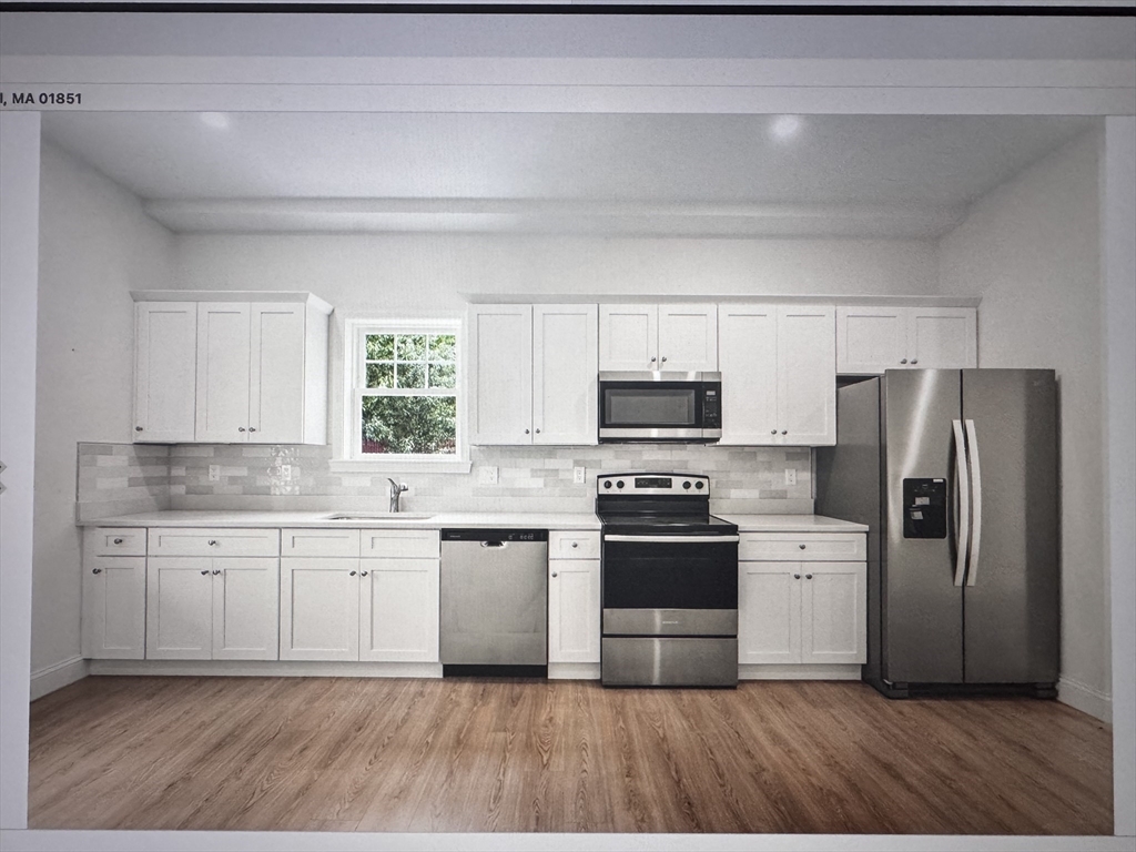 1280 Middlesex Street, Unit 5 Lowell, MA 01851 - Photo 2 of 3 a kitchen with stainless steel appliances a stove a sink dishwasher a refrigerator and white cabinets with wooden floor