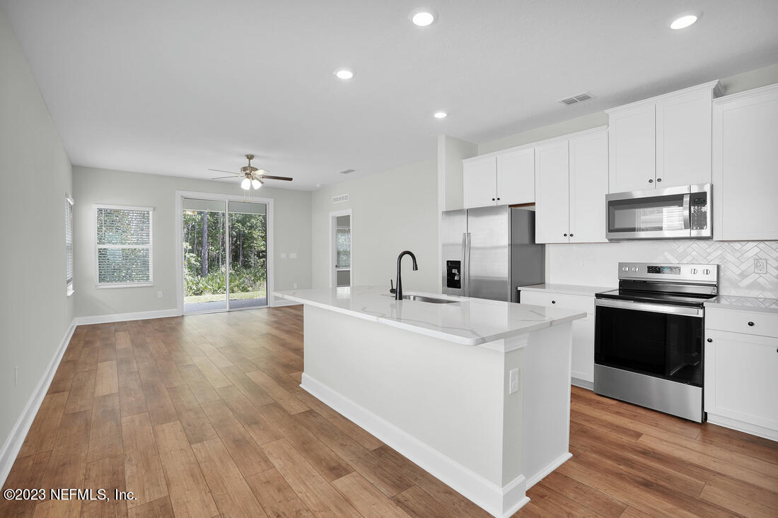 865 Morgans Treasure Road St. Augustine, FL 32084 - Photo 3 of 9 a large white kitchen with wooden floors and stainless steel appliances