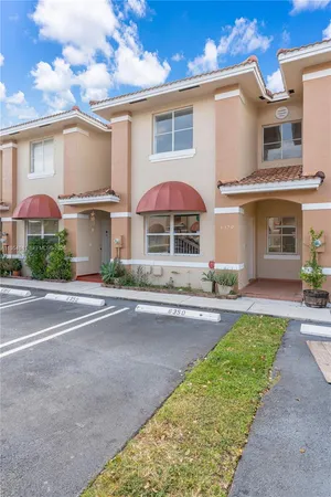 a front view of a house with a yard and potted plants