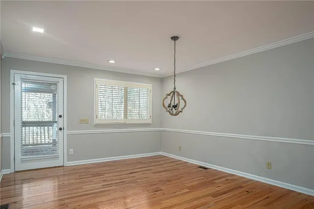 a view of an empty room with wooden floor and window