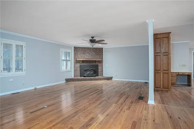 an empty room with wooden floor fireplace and windows