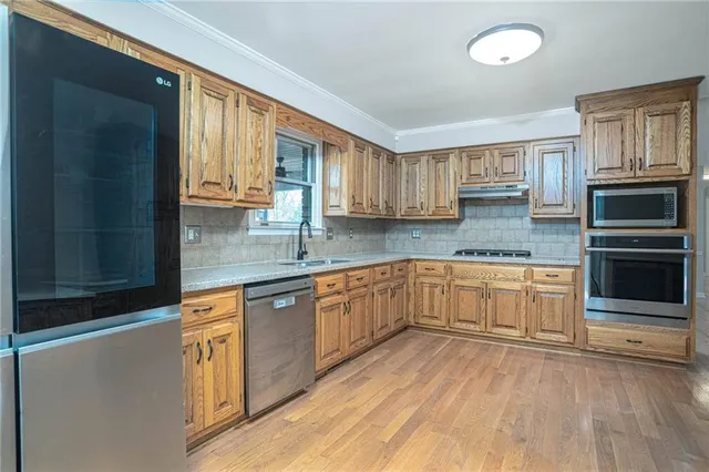 a kitchen with stainless steel appliances granite countertop a stove a sink and a microwave