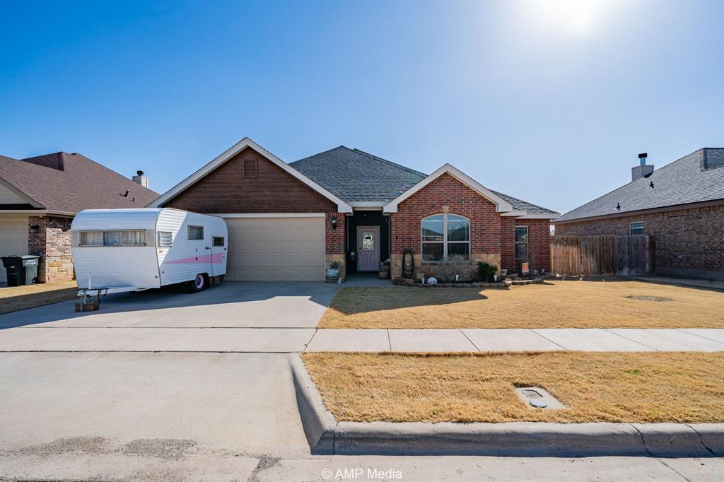 Ranch-style home featuring a front yard, roof with shingles, concrete driveway, brick siding, and a garage
