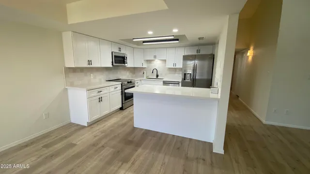 a large kitchen with stainless steel appliances granite countertop a stove a sink dishwasher and a oven with white cabinets