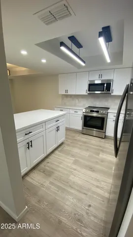a large white kitchen with stainless steel appliances granite countertop a stove and a sink