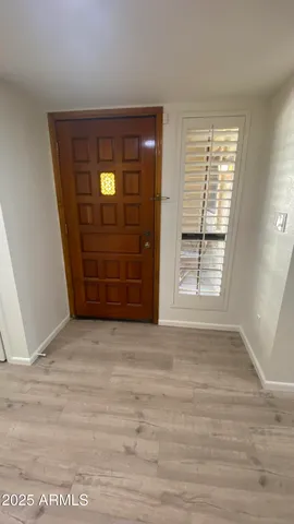 a view of an empty room with wooden floor and window