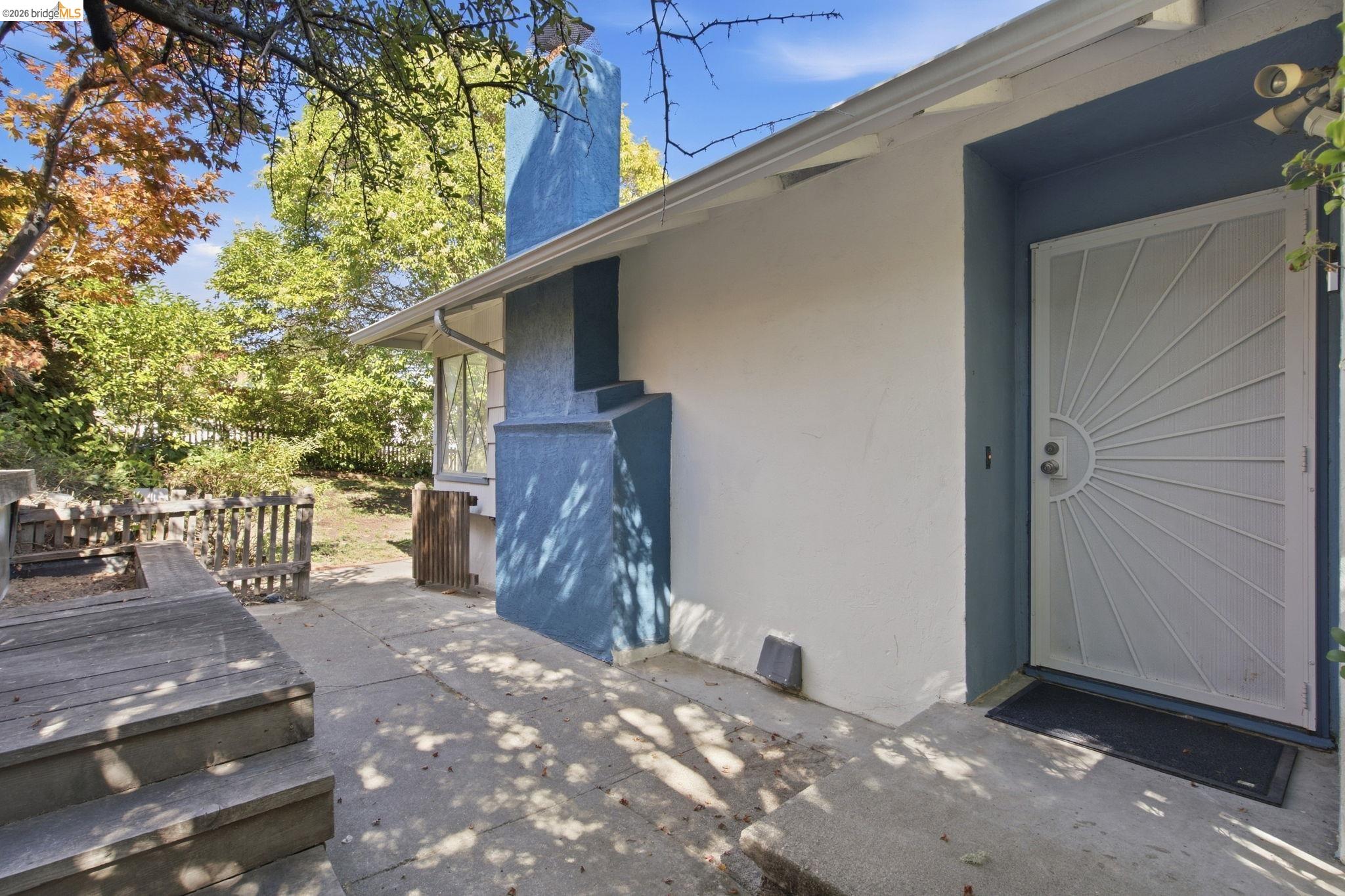 White stucco exterior with blue trim and an ornate security screen door