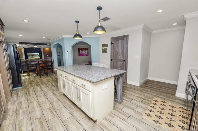 a room with wooden floor pool table and chairs