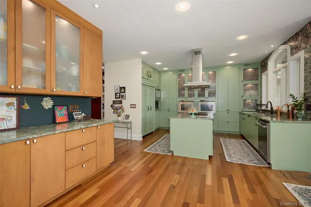 a kitchen with stainless steel appliances granite countertop a refrigerator a sink dishwasher and white cabinets with wooden floor