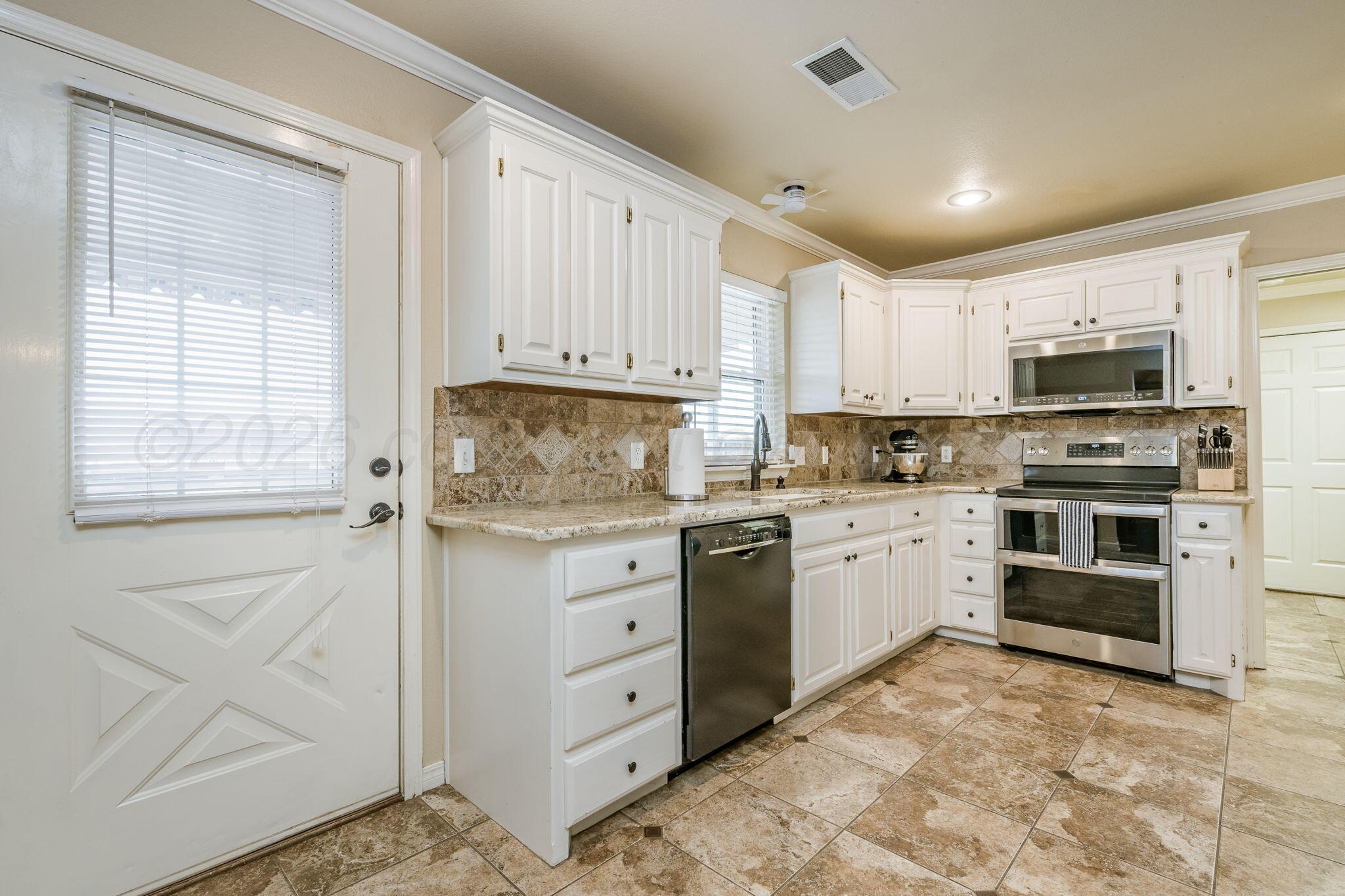 15812 Outback Trail Amarillo, TX 79118 - Photo 12 of 25 a kitchen with stainless steel appliances granite countertop a stove top oven a sink dishwasher and a refrigerator with white cabinets