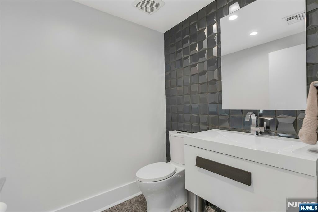 1238 River Road Edgewater, NJ 07020 - Photo 30 of 45 a bathroom with a sink a toilet and a mirror