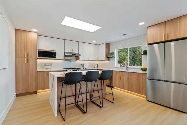 a bathroom with a granite countertop toilet a sink a mirror and a window
