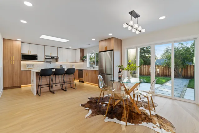 a kitchen with a refrigerator a microwave oven a sink a dining table and chairs