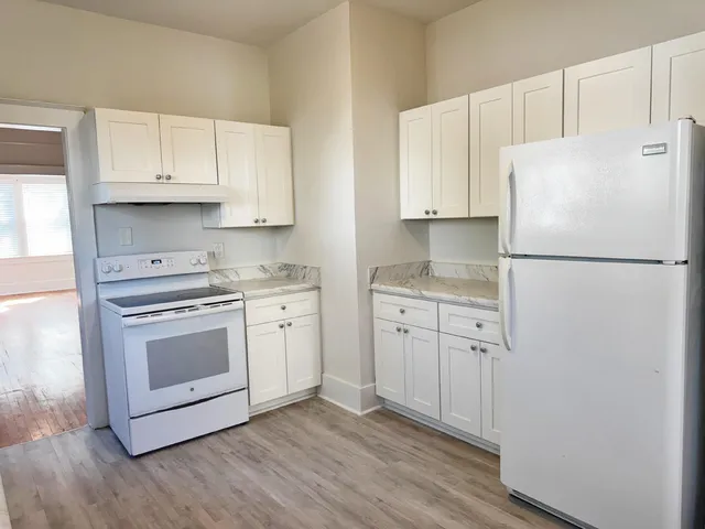 a kitchen with cabinets appliances wooden floor and a window