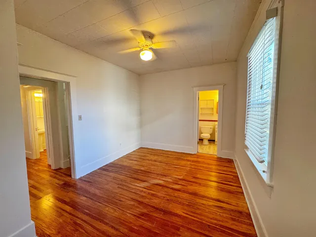a view of an empty room with window and wooden floor
