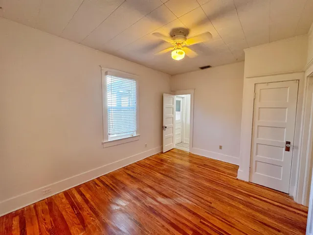 a view of an empty room with window and wooden floor