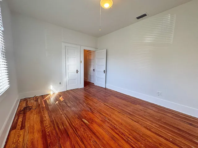a view of empty room with wooden floor and fan
