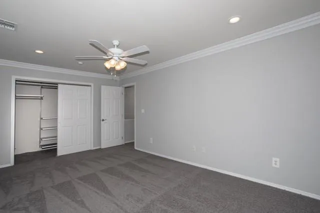an empty room with closet and a ceiling fan