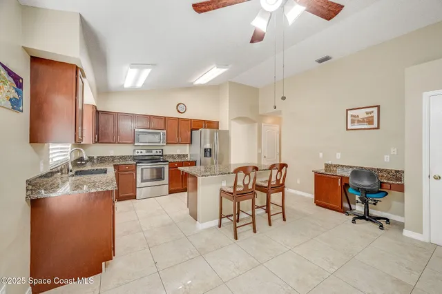 a kitchen with stainless steel appliances kitchen island granite countertop a stove a sink a dining table and chairs with wooden floor