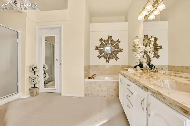 en suite bathroom with a double vanity sink a mirror a bathtub and