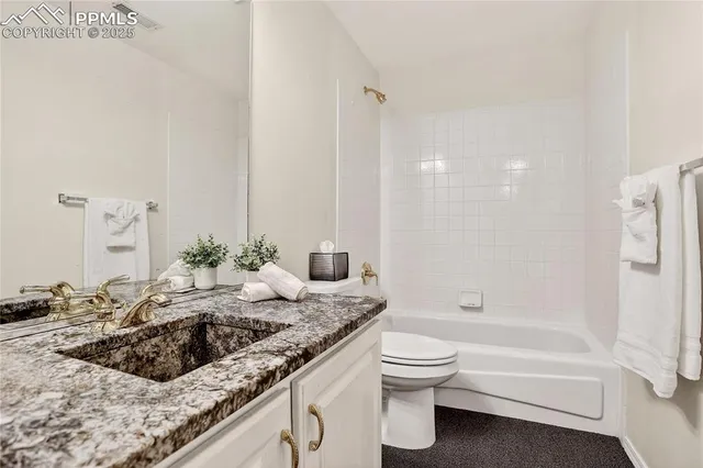 a bathroom with a granite countertop sink a toilet and bathtub