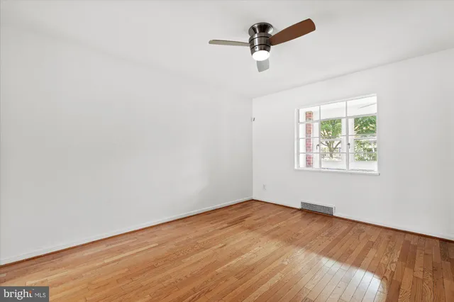 an empty room with a window and a ceiling fan