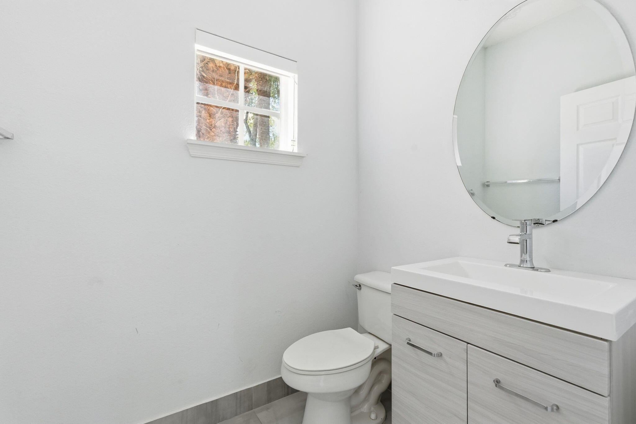 1086 Woodfield Road Greenacres, FL 33415 - Photo 13 of 32 a bathroom with a toilet a sink and mirror