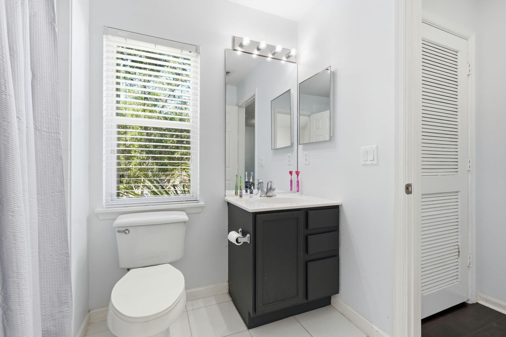 1086 Woodfield Road Greenacres, FL 33415 - Photo 23 of 32 a bathroom with a toilet sink and mirror