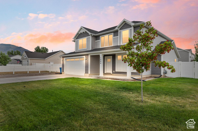View of front of home with concrete driveway, an attached garage, and a porch