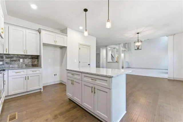 a kitchen with stainless steel appliances granite countertop a sink a stove and a wooden floors