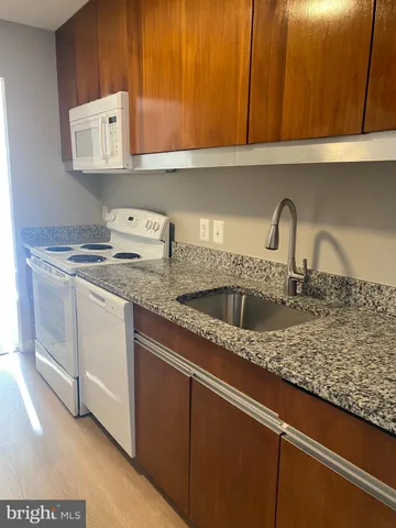 a kitchen with granite countertop a sink a stove and refrigerator