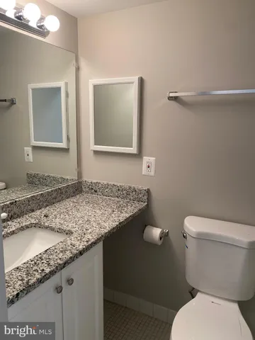 a bathroom with a granite countertop toilet and a sink