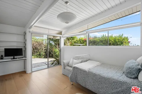 a bedroom with a bed and large windows