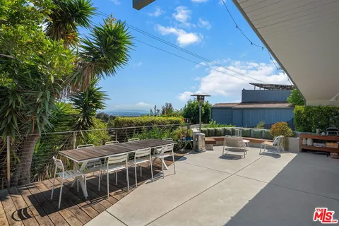 a view of a roof deck with table and chairs with wooden floor and fence